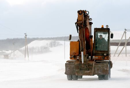 RAEVKA, RUSSIA - FEBRUARY 22, 2019: An earthmover crane moves along a snow road in Raevka during the witner months. These machines are used to clear snow from roads.のeditorial素材