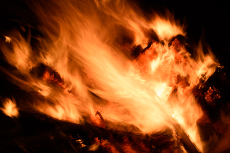 Burning raging fire at night with intentional movement of the flames creating a dynamic light effect and intentional blurred motionの写真素材