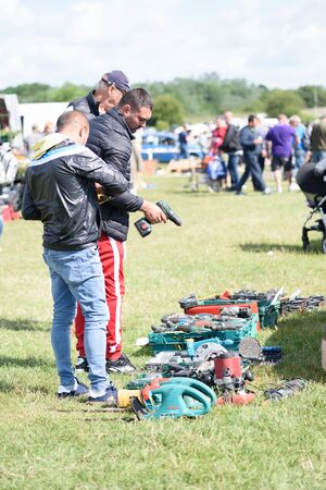 CHELMSFORD, ESSEX/ENGLAND - 1ST JUNE 2019 - Men visiting a car boot sale in Boreham Essex where they are looking at drills and tools for work and can also buy cheap and unusual items during the summer of 2019のeditorial素材