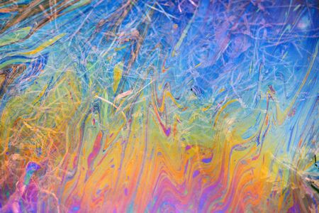 Toxic colours of oil and water in a chemical spill creating a psychedelic blur of rainbow colours. Copyspace area for environmental and pollution based themes and designs.の写真素材