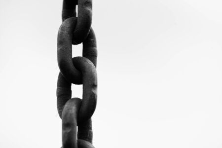 Metal chain in a closeup view with blue sky and clouds with copyspace area for freedom slavery...