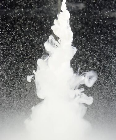 White unknown liquid drops into clear water creating a mix of liquid and oilsの写真素材