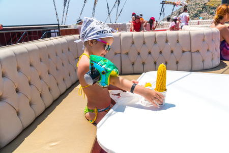 The child on the upper deck of the ship - the little girl is going to eat corn on the cobの写真素材