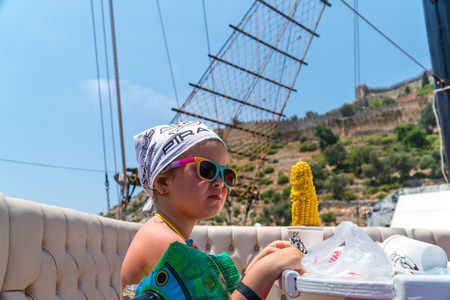 The child on the upper deck of the ship - the little girl is going to eat corn on the cobの写真素材