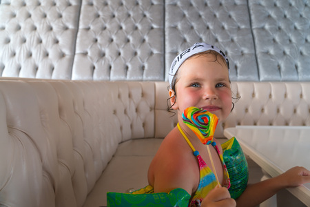 Little girl after swimming is to eat colorful Lollipopの写真素材
