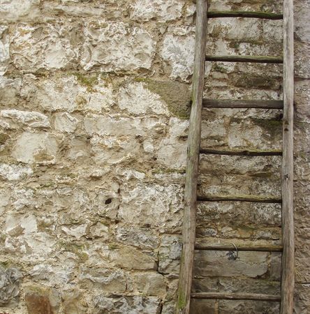 vintage wooden ladder in front of an old stone wallの写真素材
