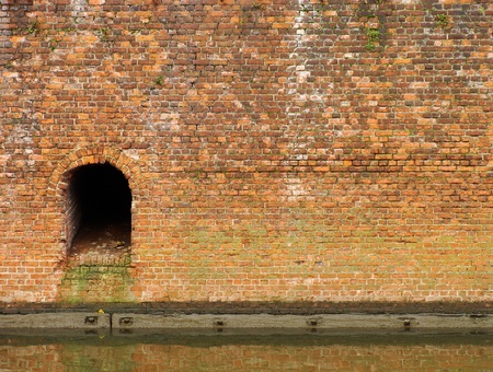 old worn wall near water with sewer exit                               の写真素材