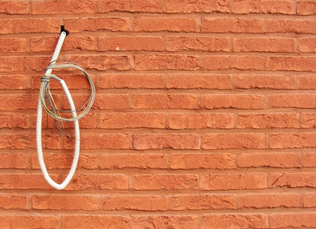 electricity wire hanging on red brick wall                               