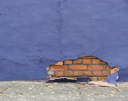sidewalk with blue damaged wall showing bricks                            の写真素材