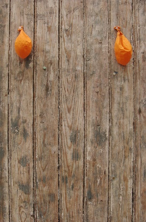 2 deflated orange balloons on worn grungy wood panel     の写真素材