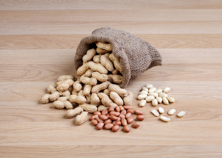 Peanuts in the bag sack isolated on wooden table 