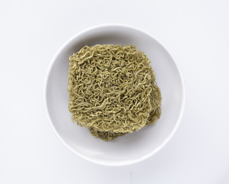 Instant dried green noodles in a white bowl isolated on white backgroundの写真素材