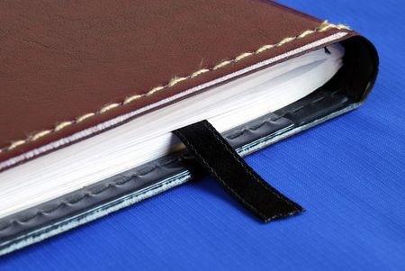 Brown notebook with a black bookmark isolated on blueの写真素材