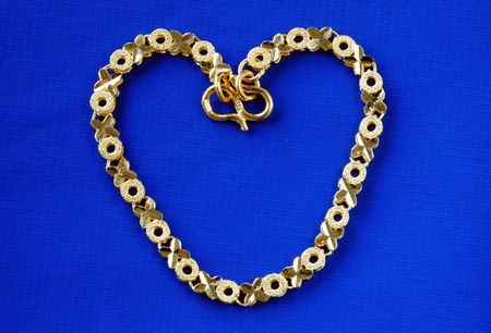 Close up view of a 24K gold bracelet isolated on blue