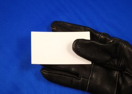 Blank business card on a black glove concepts of invitation or introduction isolated on blueの写真素材