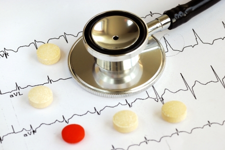 A stethoscope on the top of the EKG chart with pills concept of modern medicineの写真素材
