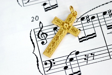 A golden cross on the top of a music sheet concept of religionの写真素材