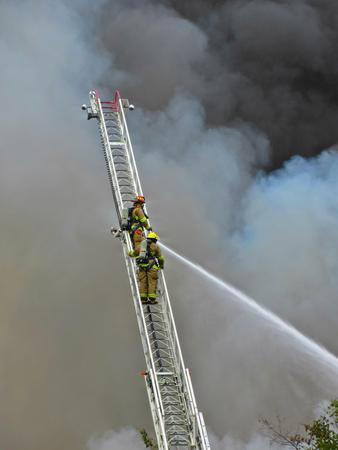 Firefighters on aerial ladder surrounded by smoke.のeditorial素材