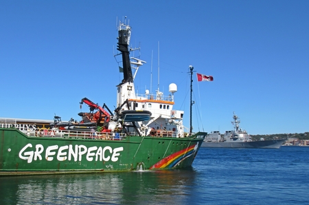 Greenpeace ship docked in Halifax as Canadian Frigate passes by on way to participate in NATO antisubmarine warfare exercises off Canada's east coast.のeditorial素材