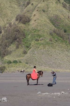 Undefined model posing on a horse under the Bromo massif. Mount Bromo is an active volcano and part of the Tengger massif in East Java. June 28 2014.のeditorial素材