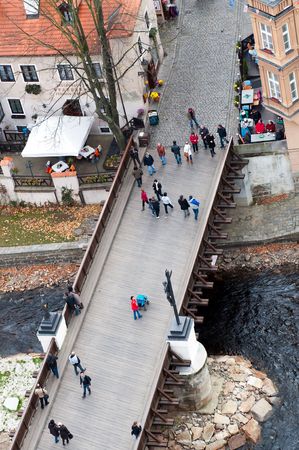 CESKY KRUMLOV, CZECH REPUBLIC - 23 OCTOBER, 2010: Tourists walk over old wooden bridge in Cesky Krumlov on October 23, 2010.  Cesky Krumlov is a UNESCO World Heritage Site since 1992.のeditorial素材