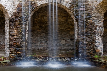 Waterflows in a park, stony wall on the background.の写真素材