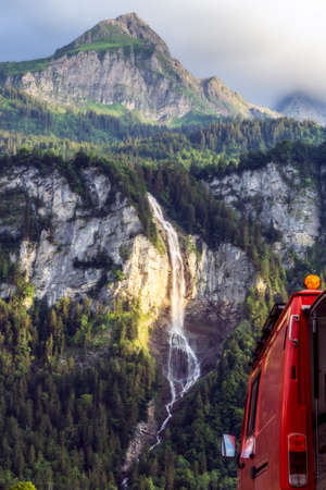 Suisse waterfall behind red firetruck vanlife camperの写真素材