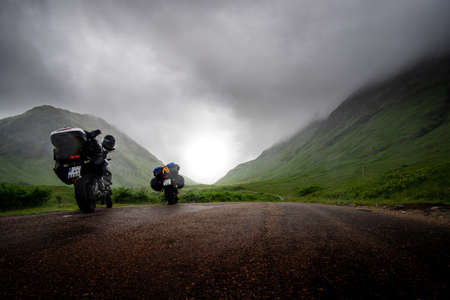 two motor bikes on road trip on small scottish road on foggy and misty dayの写真素材