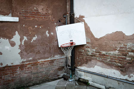 worn basket ball hoop hanging low in streets of veniceの写真素材
