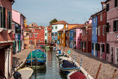 Burano canal with boats lined with colored housesの写真素材