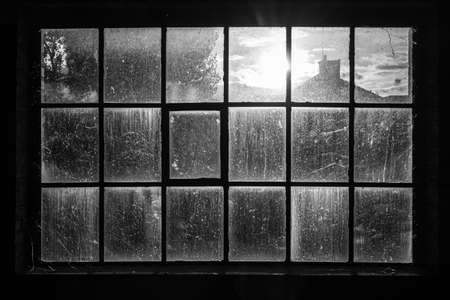 Dirty window in abandoned factory with sun shining throughの写真素材