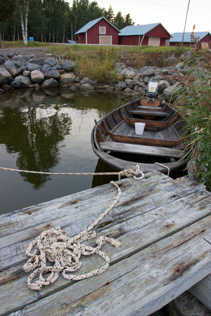 Wooden boat standing in pier tied with rope with red houses の写真素材