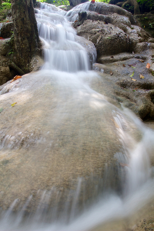 Small waterfall in Erawan National Park in close-up with water flowing over big rockの写真素材