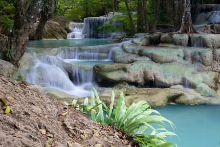 Beautiful waterfall cascade in Erawan National Park with green plant in foregroundの写真素材