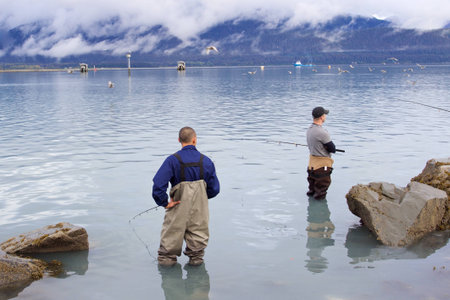 Seward, Alaska, United States - September 10, 2014: Two men in their 30s standing in ocean and fishing salmon in Resurrection Bay in Seward, Alaskaのeditorial素材