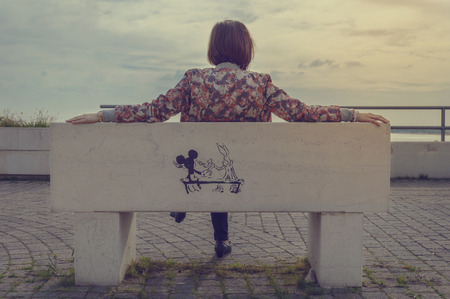 a girl sitting on a benchのeditorial素材