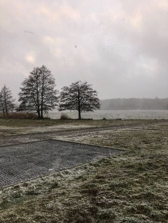 Big snow storm above the pond. There are some trees in front of the pond. It's winter time.の写真素材
