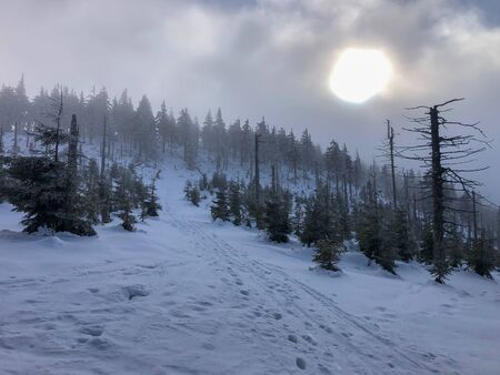 Cloudy weather with clouds and sun in winter mountainsの写真素材