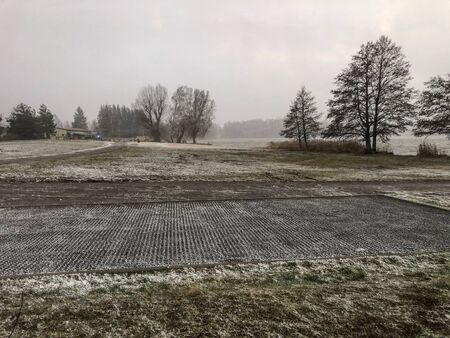 Snow storm in winter at the pond with trees and parking placeの写真素材