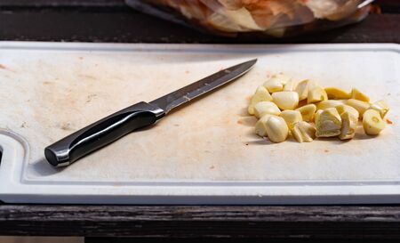 Sliced garlic and sharp knife lying on cutting board