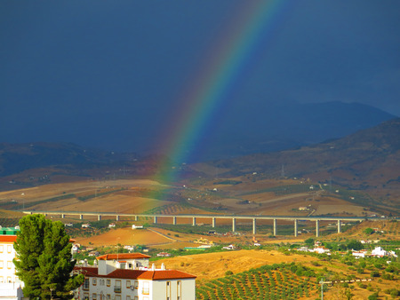 Rainbow hitting house on hill in Guadalhorce Valley, Andaluciaの写真素材