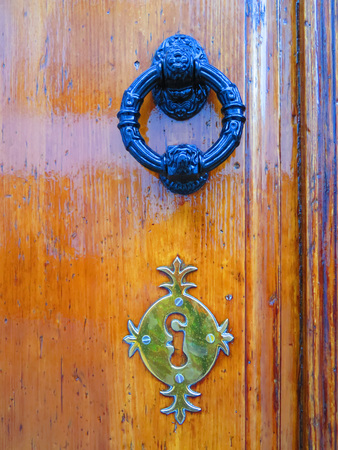 Varnished wooden door with ornate knocker and fake keyholeの写真素材