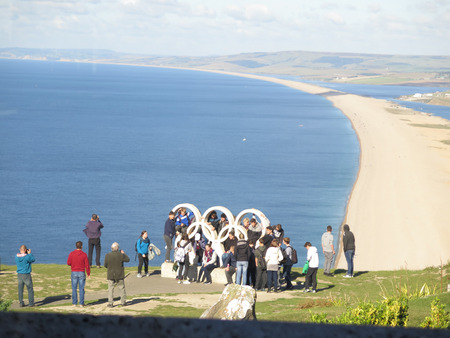 Portland, England - October 9, 2016: Group of students climbing the Five ring monument overlooking Portland Beachのeditorial素材