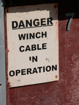 Warning Sign on Winch Cable Building on beach in Village of Beer in Devon UKの写真素材