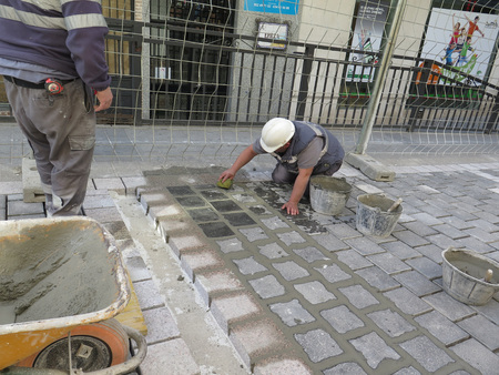 Alora, Spain - March 22, 2017: Men working on grouting newly laid road stones in village streetのeditorial素材
