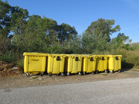 Collection of yellow recycling containers on rural road sideの写真素材
