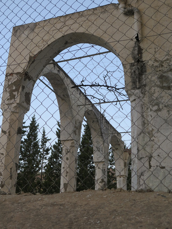 Arches by Abandoned building behind wire fence             の写真素材
