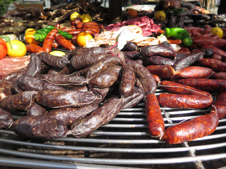 A variety of smoked and cooked meats and sausages on large round barbeque at Almeria fair, Spainの写真素材