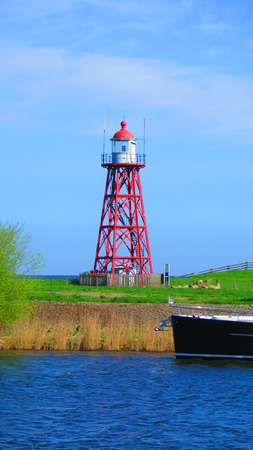Tall steel skeleton lighthouse on dike facing inland sea in Holland
