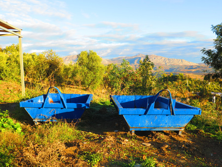 Two empty blue builder's skips on wasteland in Andalusian countryside